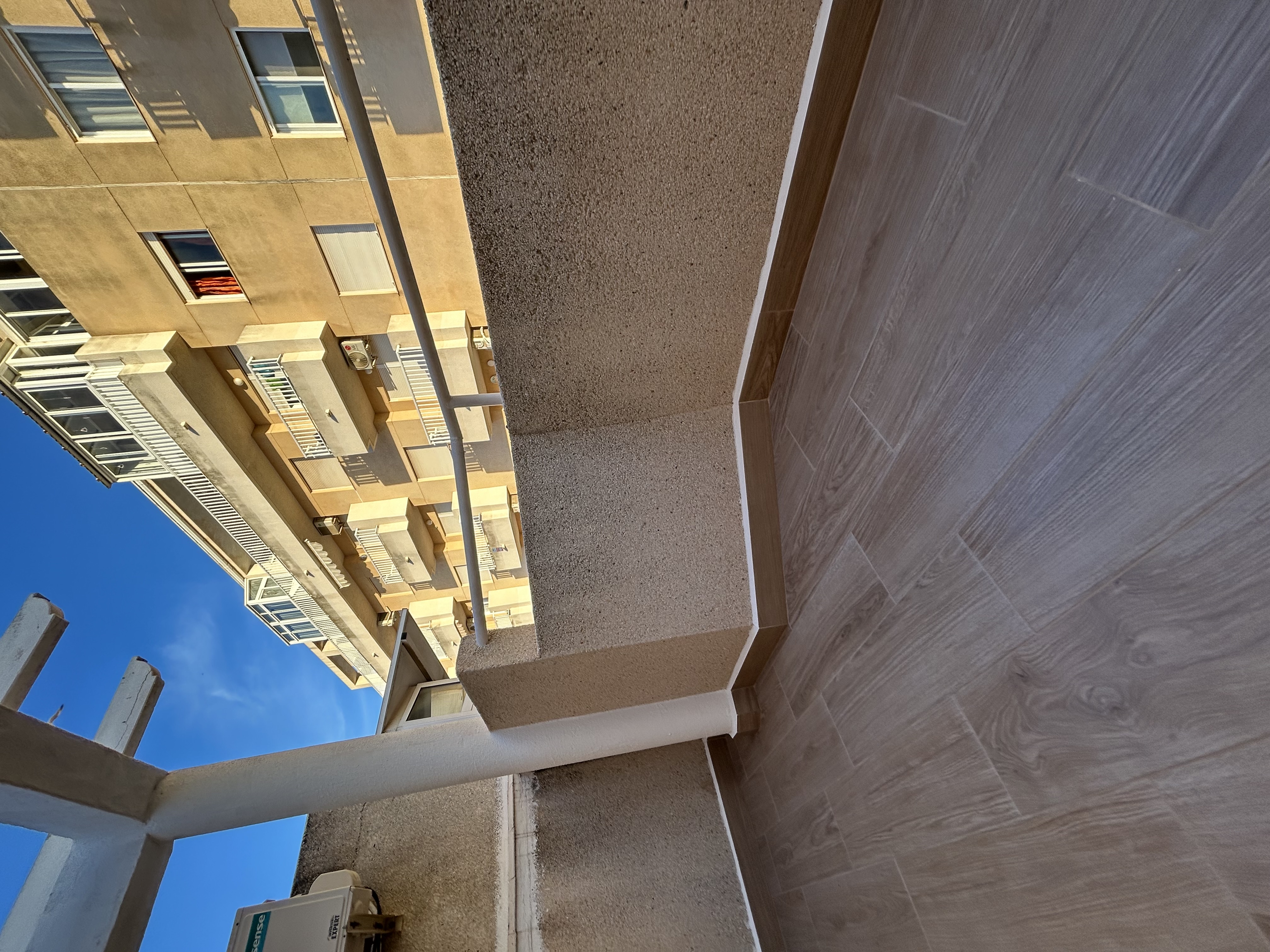 Balcón reformado con azulejo madera y techo pergola